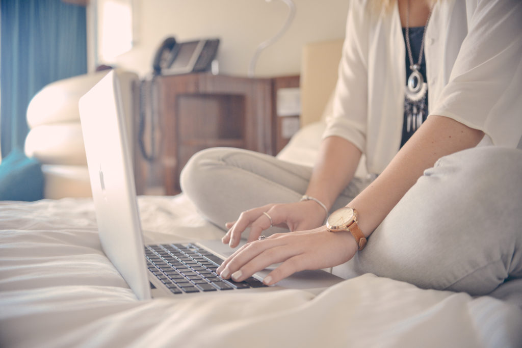 bride sitting on bed with laptop writing vows